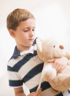 Boy (6-7) hugging his teddy-bear. Photo : Daniel Grill
