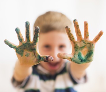 Young boy (6-7) showing hands stained with paint. Photo : Daniel Grill