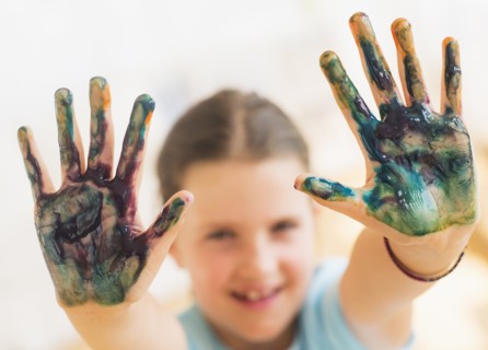 Young girl (8-9) showing hands stained with paint. Photo : Daniel Grill