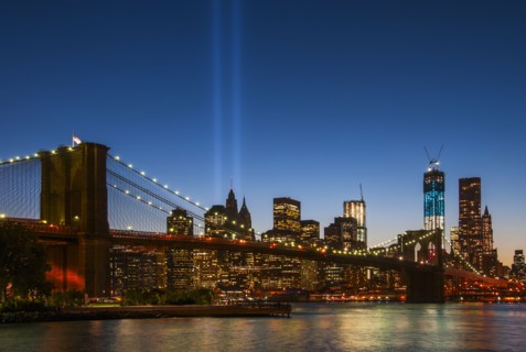 View over Hudson River towards Manhattan with September 11th memorial lights and Brooklyn Bridge.