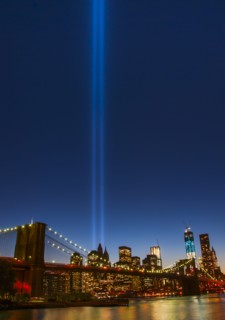View over Hudson River towards Manhattan with September 11th memorial lights and Brooklyn Bridge.