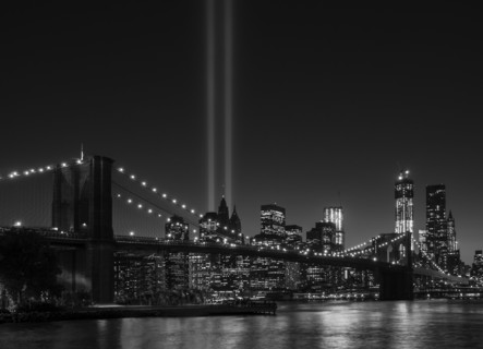 View over Hudson River towards Manhattan with September 11th memorial lights and Brooklyn Bridge.