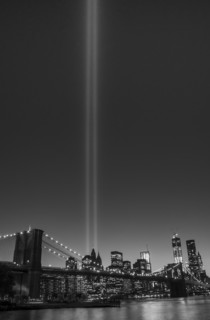 View over Hudson River towards Manhattan with September 11th memorial lights and Brooklyn Bridge.