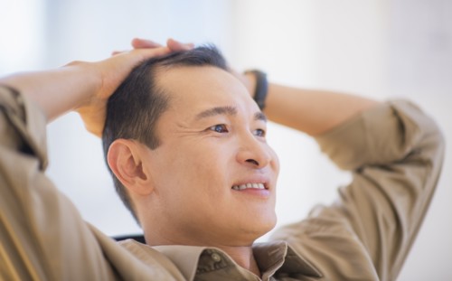 Profile of happy mid adult man with hands behind his back. Photo : Daniel Grill