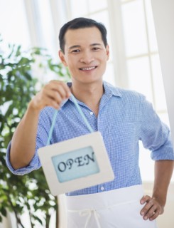 Mid adult waiter holding open sign. Photo : Daniel Grill
