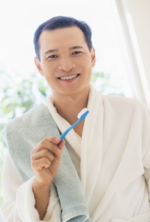 Happy mid adult man holding toothbrush. Photo: Daniel Grill