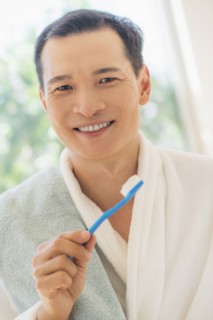 Happy mid adult man holding toothbrush. Photo: Daniel Grill