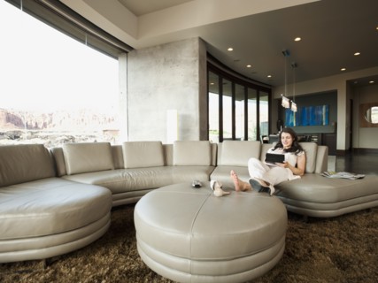 Young attractive woman using digital tablet while sitting in her living room. Photo: Erik Isakson