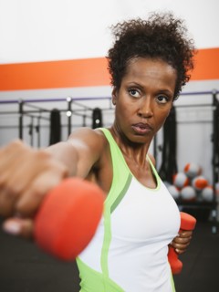 Mid adult woman exercising with dumbbells.