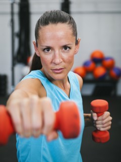 Mid adult woman exercising with dumbbells.