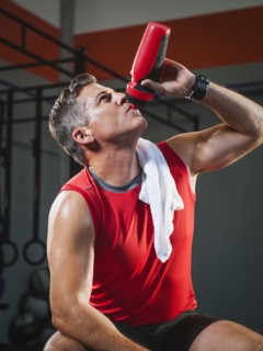 Mature man taking break from exercising to drink some water.