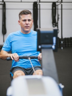 Mature man exercising on row machine in gym.