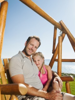 Portrait of father with daughter (4-5) on swing.