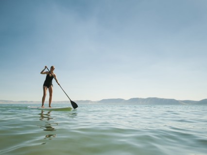 Young woman standing on paddleboard.