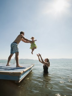 Parents playing with their daughter (2-3) in lake. Photo: Erik Isakson