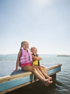 Girls (2-3, 4-5) sitting at the edge of raft in life jackets.