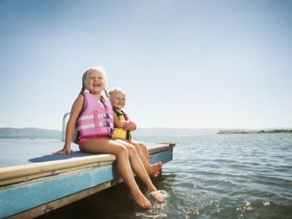 Girls (2-3, 4-5) sitting at the edge of raft in life jackets.