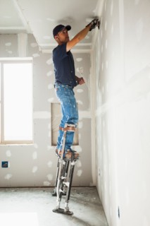 Drywall worker on stilts working on drywall joints. Photo: Mike Kemp