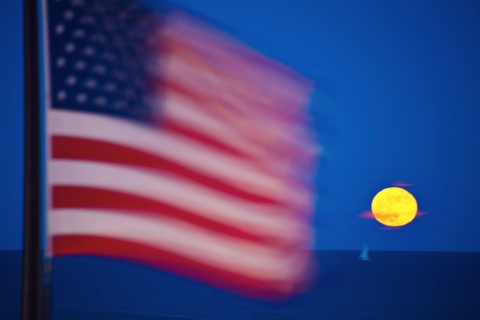 Flag and rising moon over Lake Michigan. Photo : Henryk Sadura