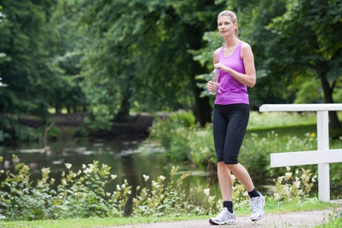 Young woman walking over a bridge with a bottle of water in her hand