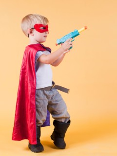 Studio shot, Portrait of boy (2-5 years) wearing cape and holding toy gun. Photo : Jessica Peterson
