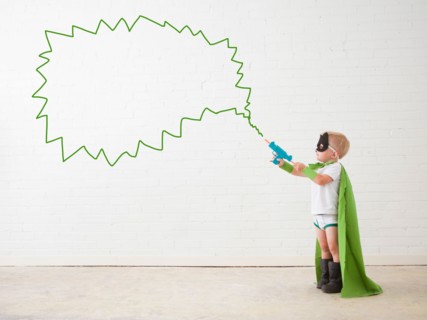 Studio shot, Portrait of boy (2-5 years) wearing green cape and holding his toy gun. Photo :