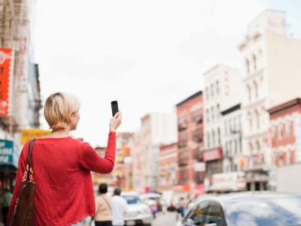 Woman taking picture with her mobile phone on street. Photo : Jessica Peterson