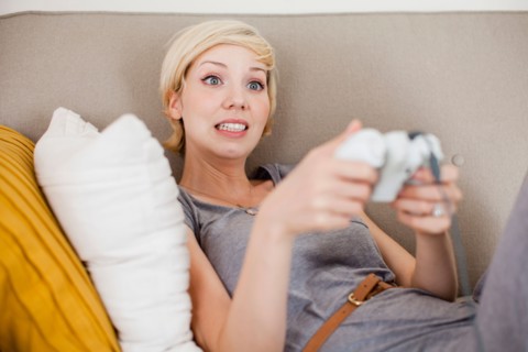 Woman laying on sofa and playing video game. Photo : Jessica Peterson