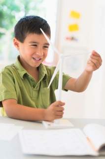 Boy (6-7) holding scale model of wind turbine.