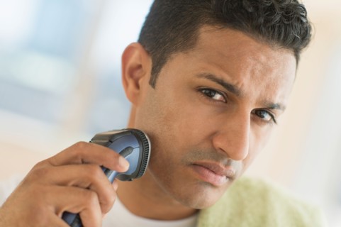 Man shaving with electric razor.