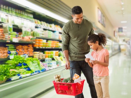 Father with daughter (6-7) shopping in supermarket.