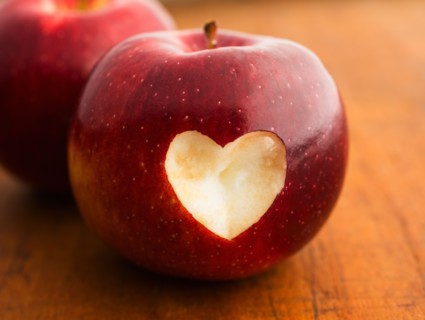 Close up of apple with missing bite in heart shape, studio shot.