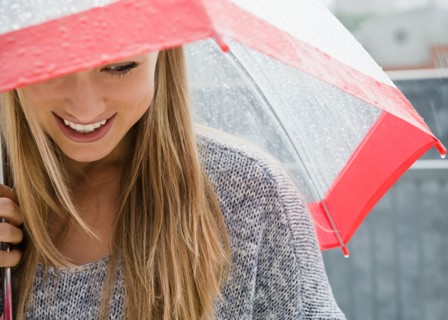 Smiling young woman with umbrella in rain