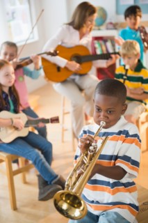 School children (8-9) with teacher playing instruments during music class