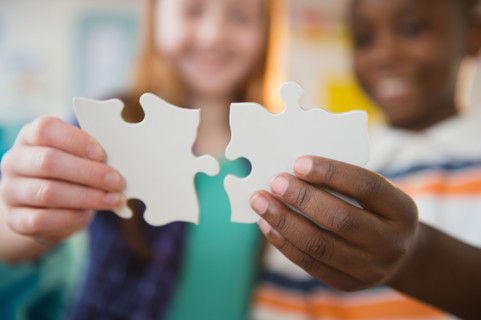 Close up of children's (8-9) hands holding jigsaw pieces