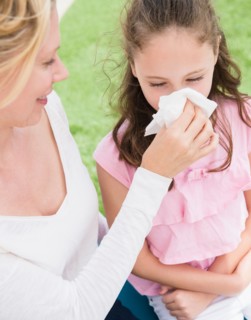 Mother helping daughter (8-9 years) to blow her nose