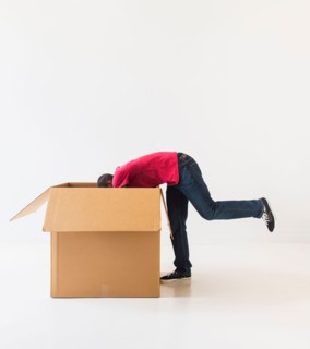 Studio shot of young man with large cardboard box