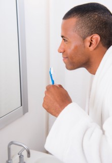 Young man with toothbrush in bathroom