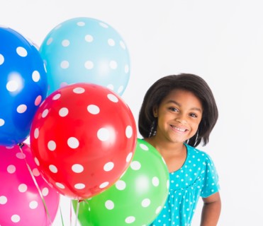 Studio shot of girl (6-7 years) with colorful balloons