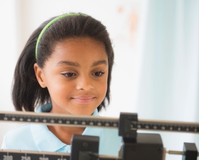 Girl (6-7 years) standing on weight scale