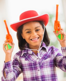 Portrait of smiling girl (6-7) with cowboy hat and toy gun