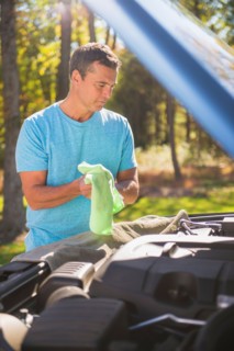 Man standing by car with hood open at roadside