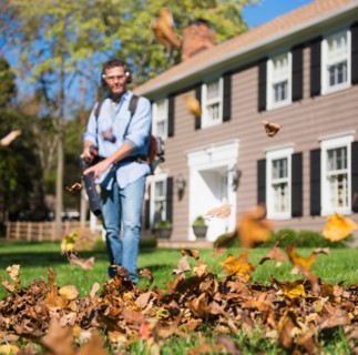 Man using leaf blower in front yard
