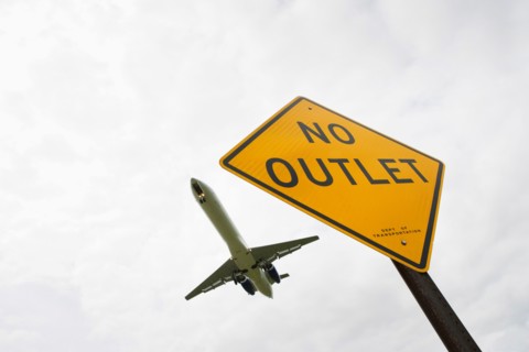 Low angle view of airplane over road sign