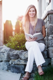 Portrait of woman sitting outdoors and holding book
