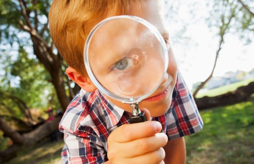 Little boy (6-7) looking through magnifying glass