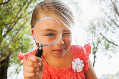Little girl (6-7) looking through magnifying glass