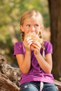 Little girl (4-5) eating peanut butter and jelly sandwich