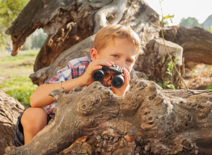 Little boy (6-7) looking at something in the distance with binoculars