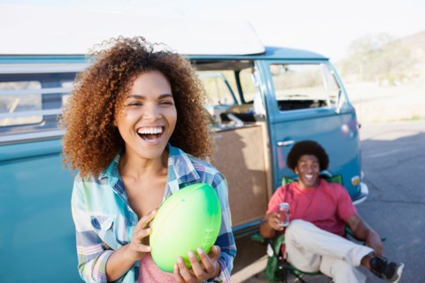 Woman in foreground holding rugby ball with friend during their road trip